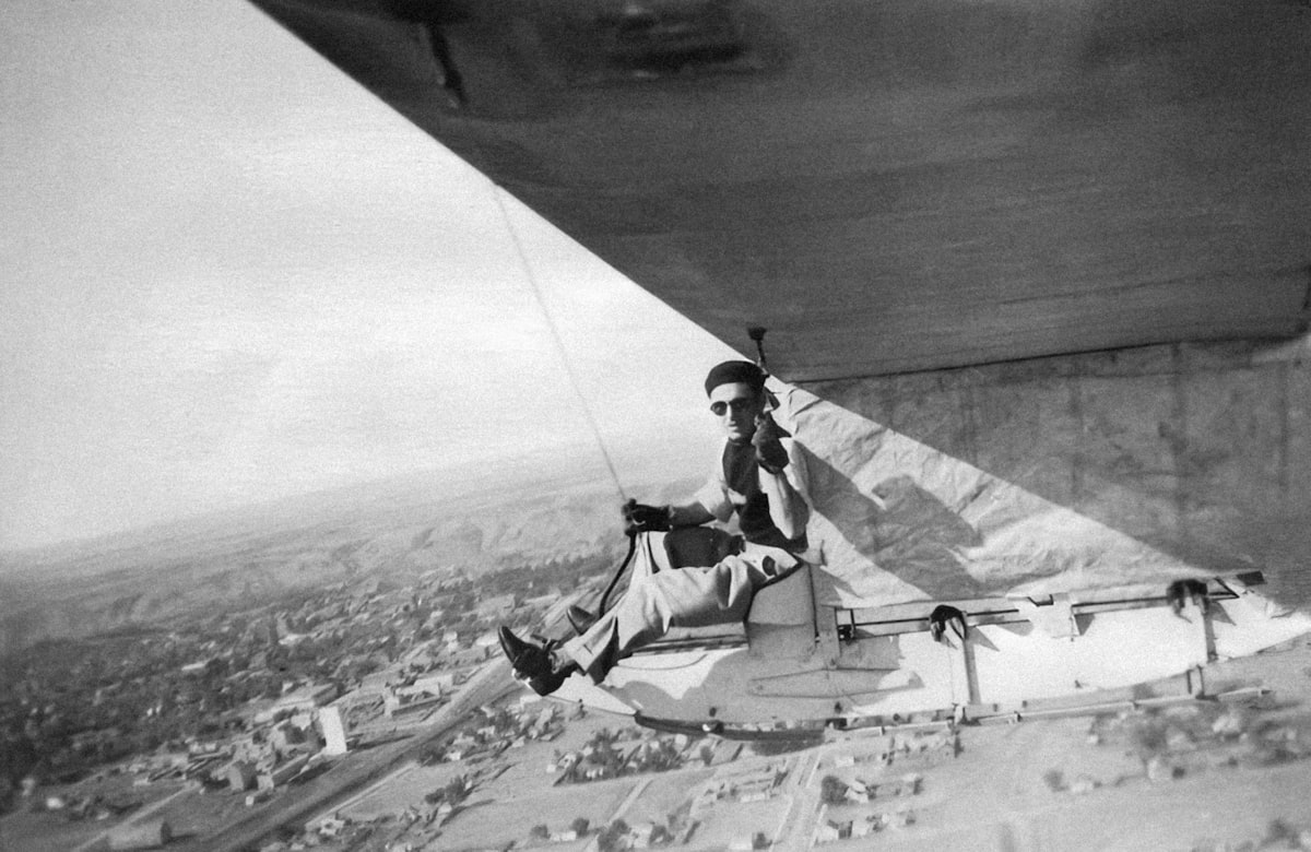 Archival photograph of a serviceman seated on the wing of an aircraft